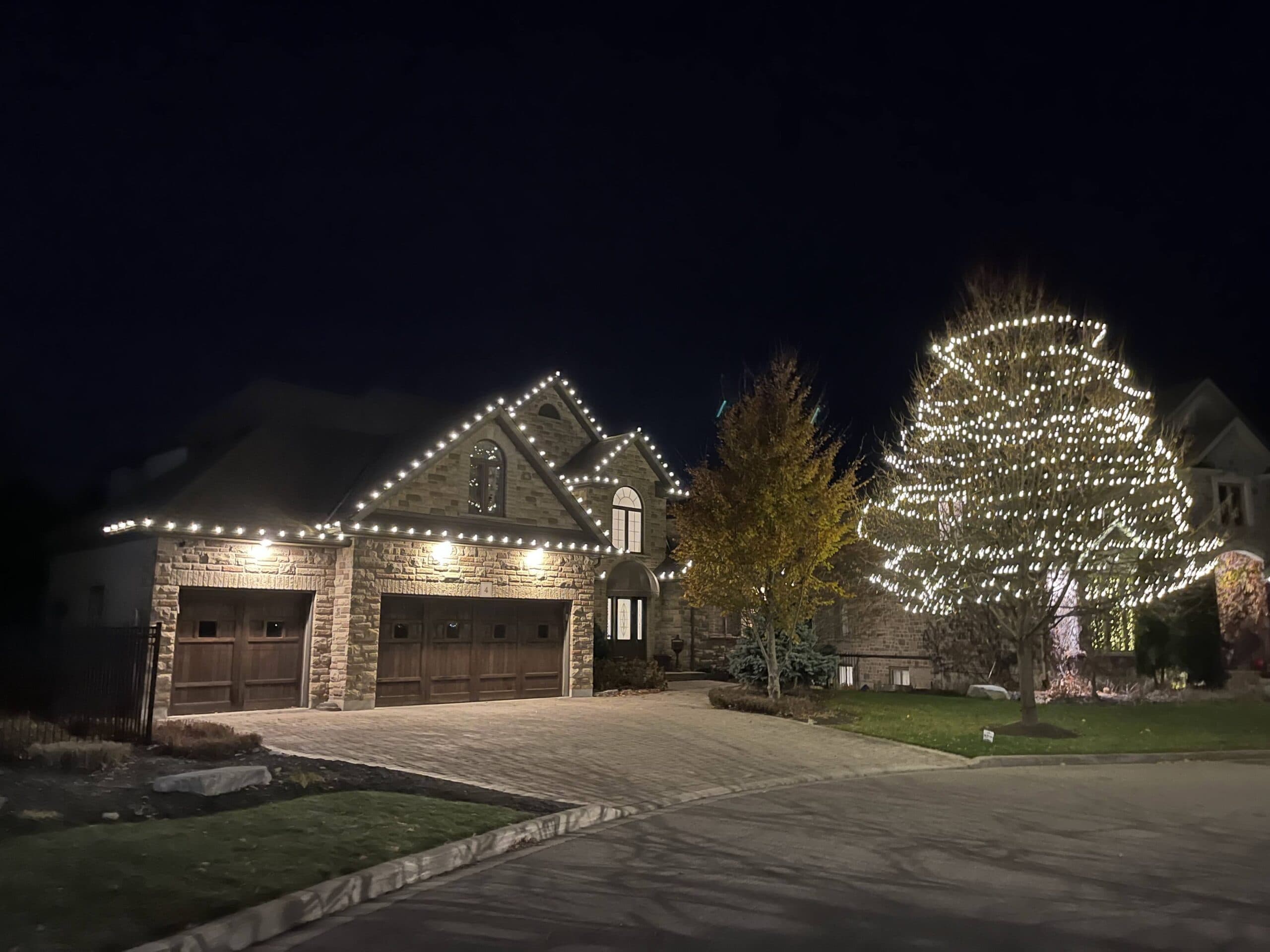 Christmas-lit two-story home in London Ontario with tree and roofline lights